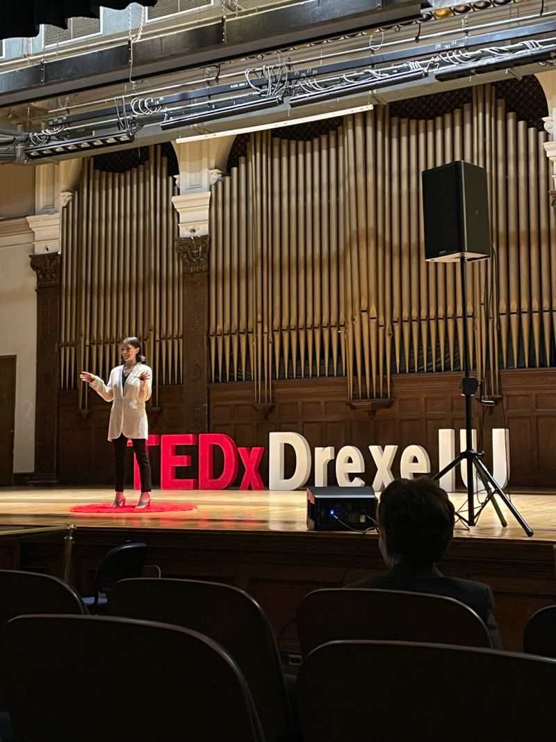 Paige standing on the Drexel Main Building auditorium stage giving a TedX talk. Photo credit to Camille Velasquez
