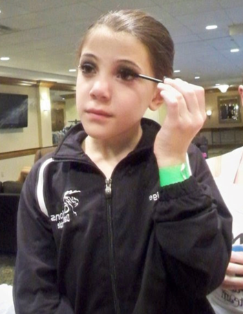 Paige applying mascara at just 8 years old before a big competition. Photo credit to Nicole DeAngelo.